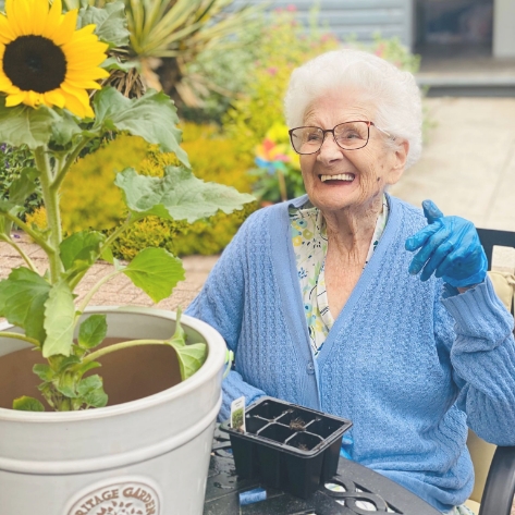 Salveo Care | One of our residents outside smiling at a sun flower