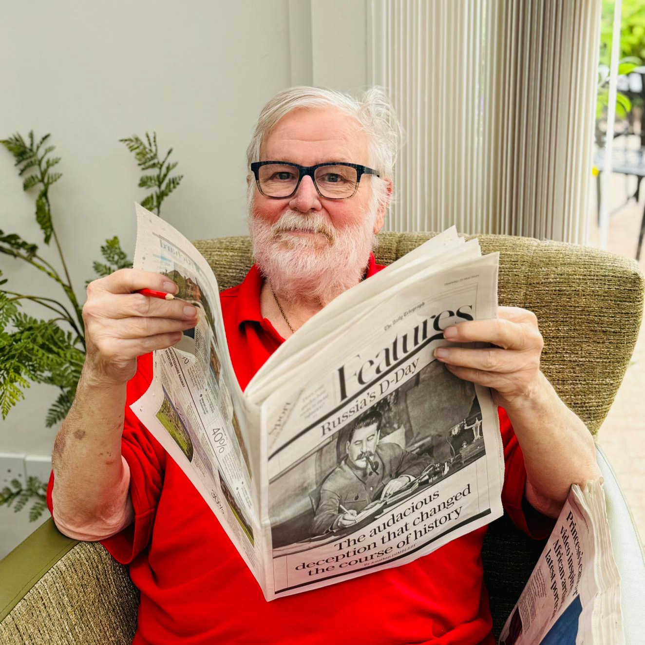 Salveo Care | One of our residents in a red turtle neck shirt reading a newspaper