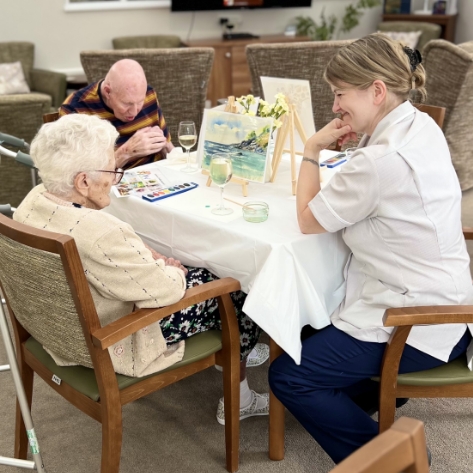 Salveo Care | Image showing our residents sat at a table interacting with a member of staff