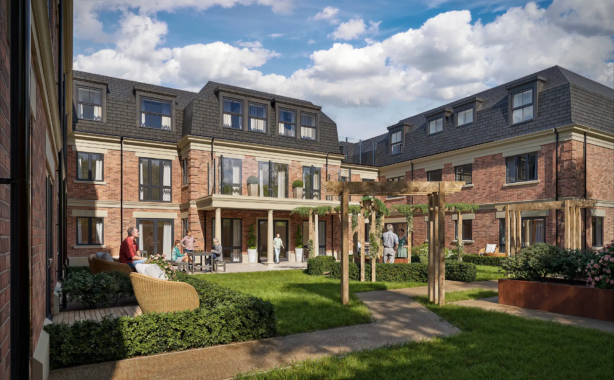 A landscaped courtyard surrounded by brick apartment blocks, with people sitting on benches, walking, and talking in the garden area under a partly cloudy sky.
